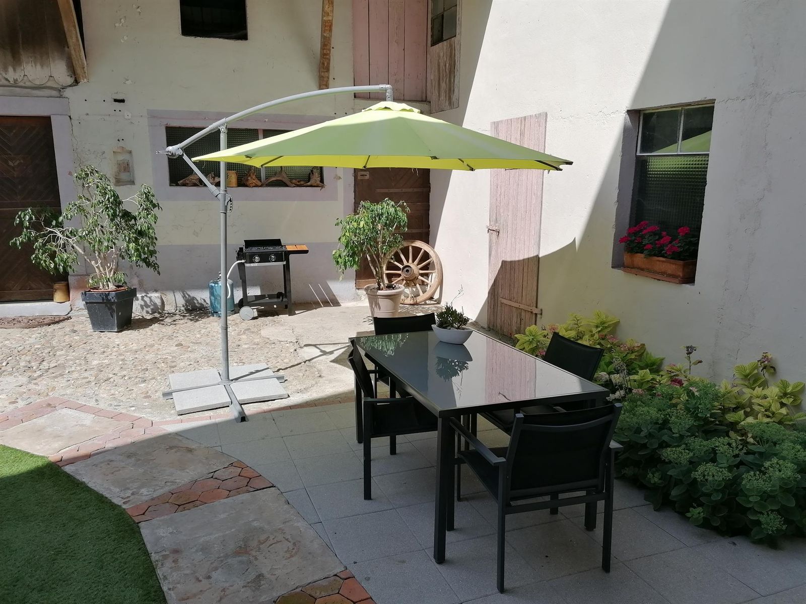 Espace extérieur avec terrasse, équipé de 4 chaises, table, barbecue  et parasol